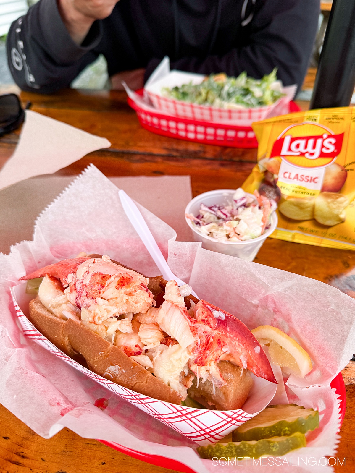 Lobster roll with a side of cole slaw and chips.