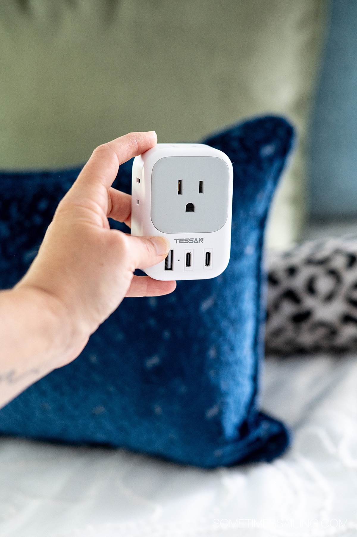 Hand holding a TESSAN travel adapter.