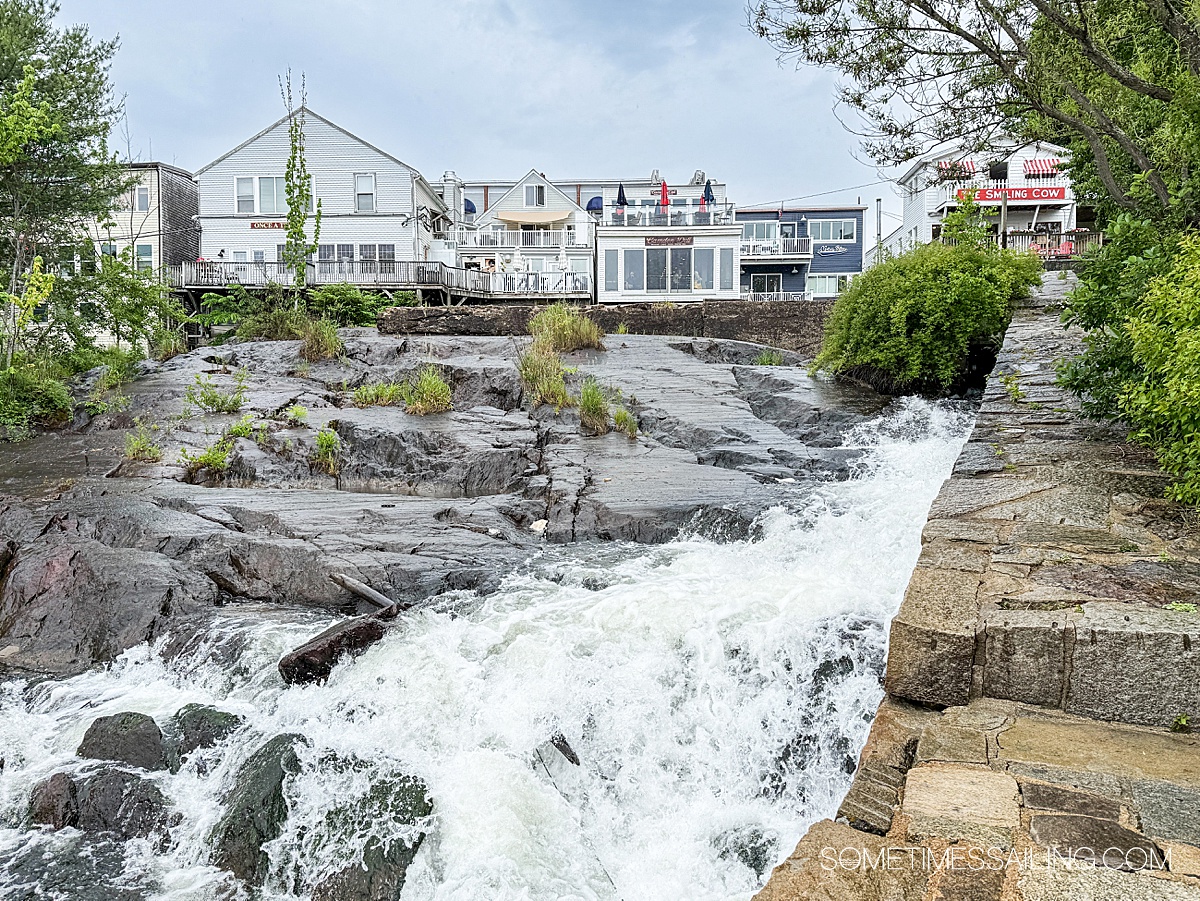 Small waterfalls with buildings in the background.