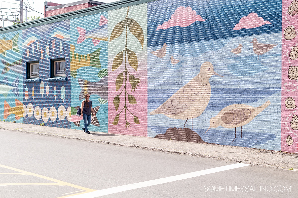 Colorful mural on the street in Rockland, Maine, with a woman in front of it.