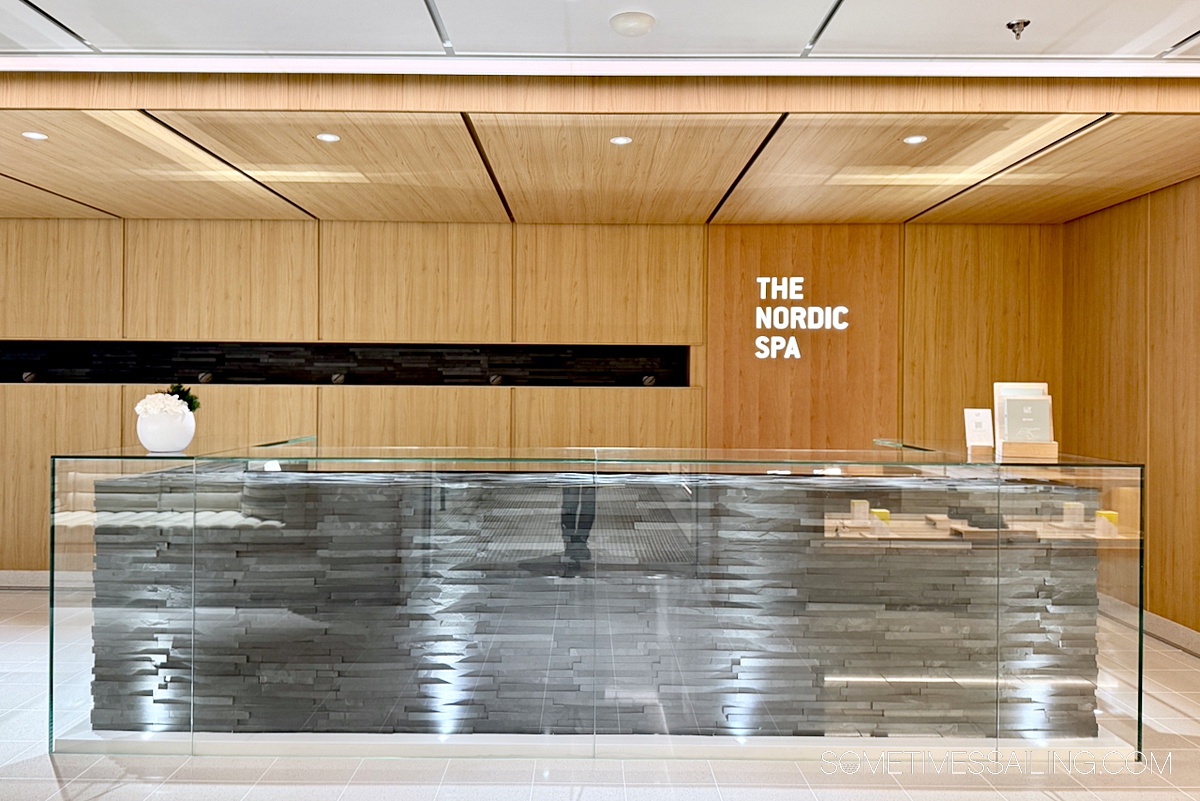 Entry to the spa area with a wood wall with neon letters and a modern desk.